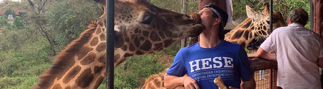 man being kissed on the face by a giraffe
