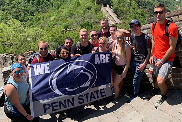 group of students posing with a Penn State flag at the Great Wall of China
